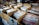 Multiple cardboard boxes filled with vinyl records are organized on tabletops. Each box has handwritten labels indicating categories of music or artists, such as Bob Dylan, The Rat Pack, and Nina Simone. The setting appears to be an indoor market or music fair.