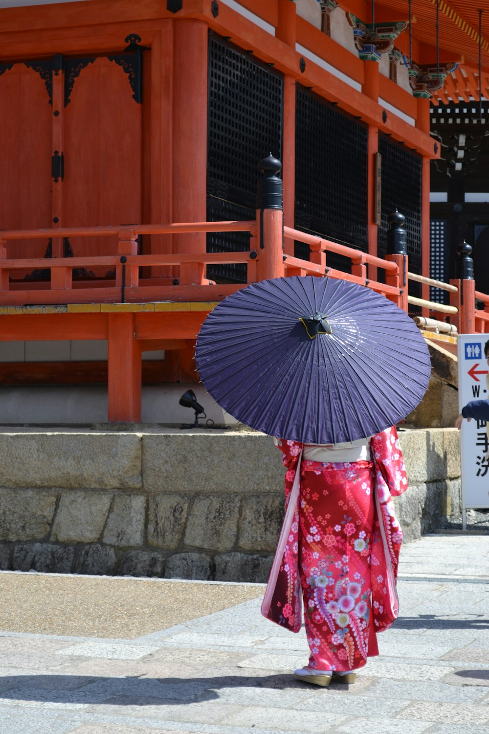 Mujer en kimono floral rojo y blanco sosteniendo paraguas azul