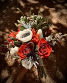 A chic flower arrangement combining red tulips and roses, shot with sharp shadows.