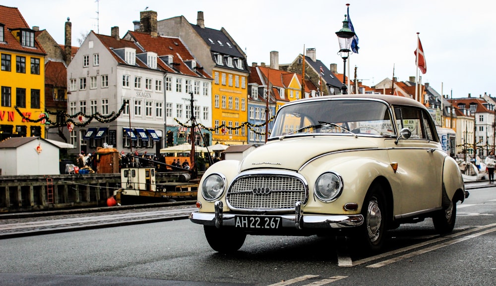 Weißer Oldtimer tagsüber auf der Straße in der Nähe von Gebäuden