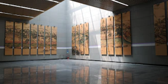 A grand gallery hall showcasing large-scale paintings from the 'Wizja' exhibition with elegant lighting.