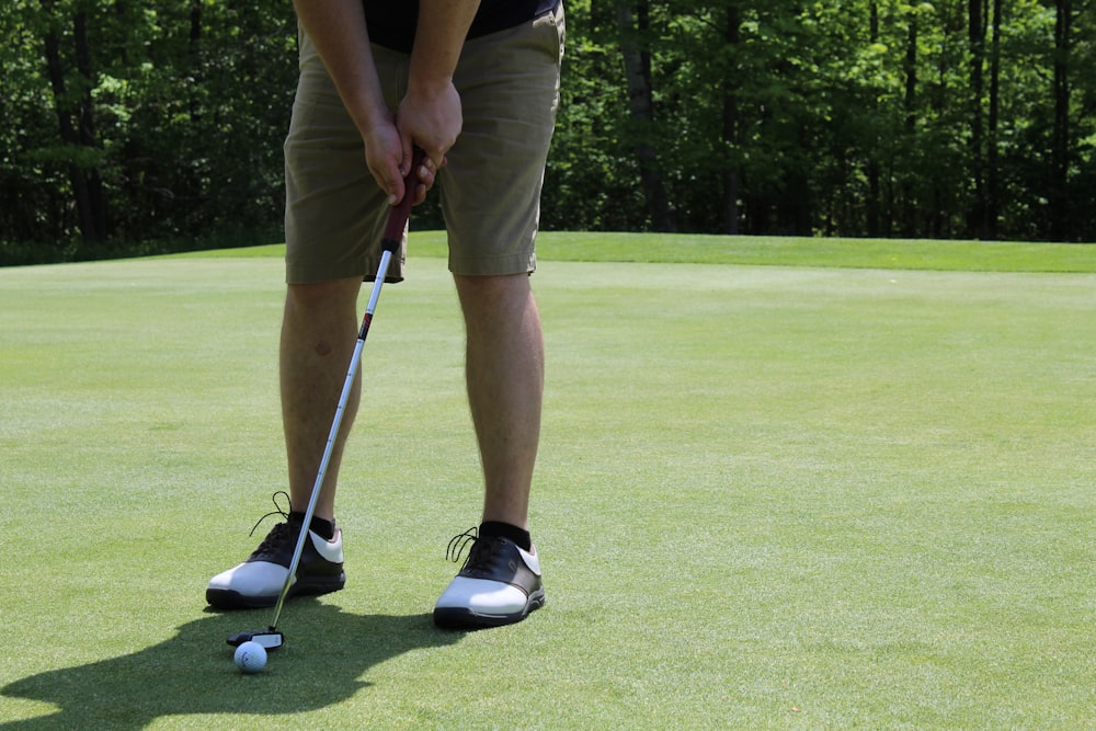 man in brown shorts and black nike shoes playing golf during daytime