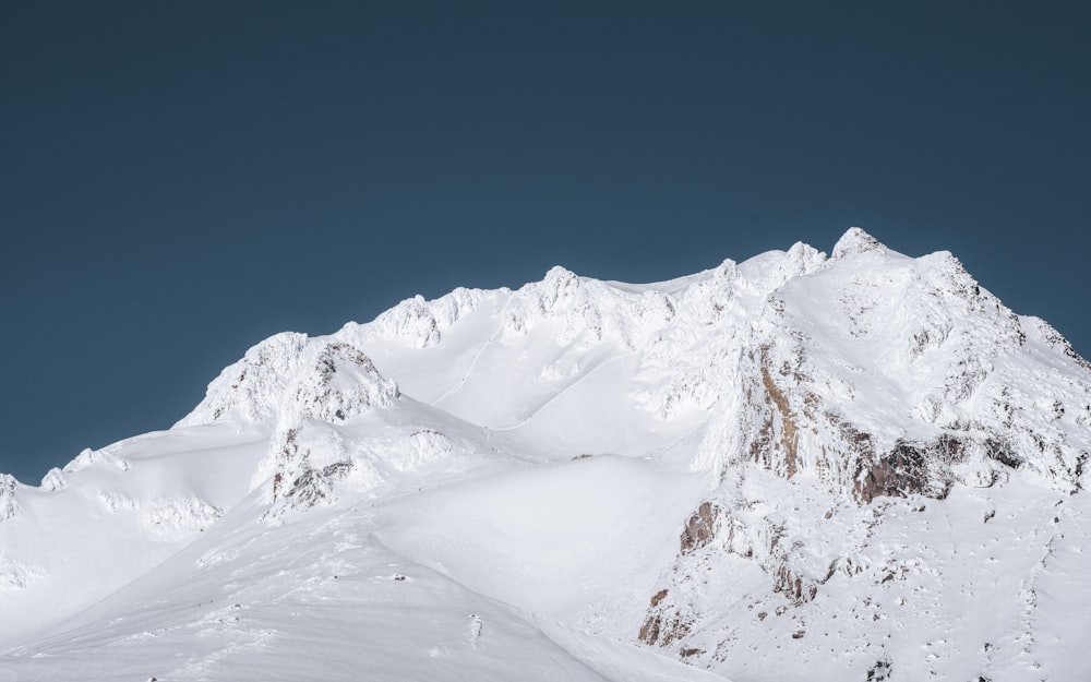 montanha coberta de neve sob o céu azul durante o dia