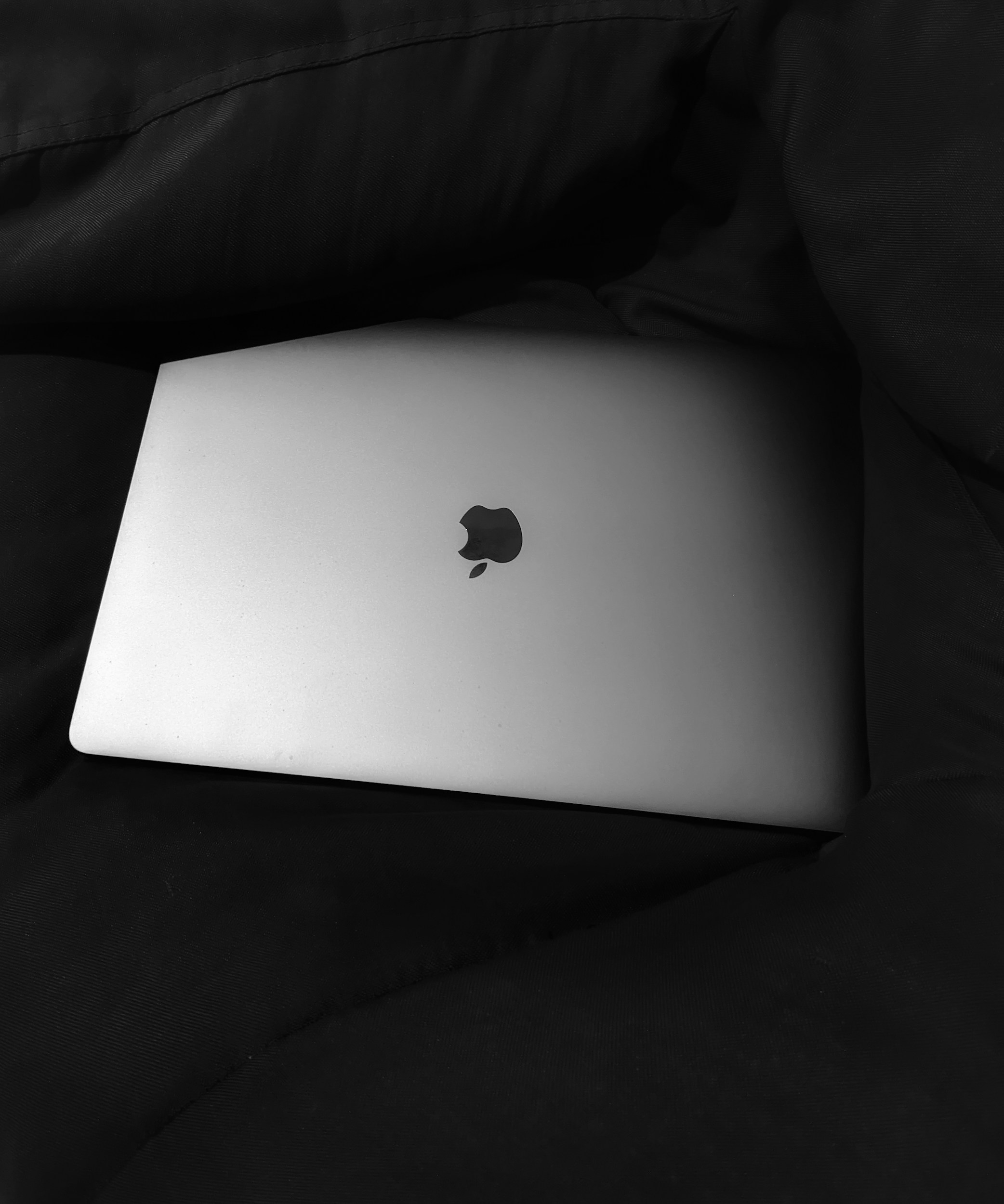 silver macbook on black textile