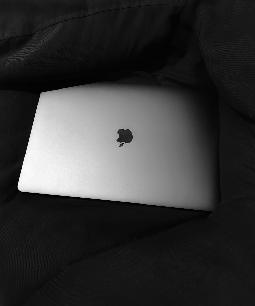 silver macbook on black textile