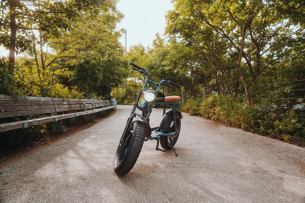 black motorcycle parked beside green trees during daytime