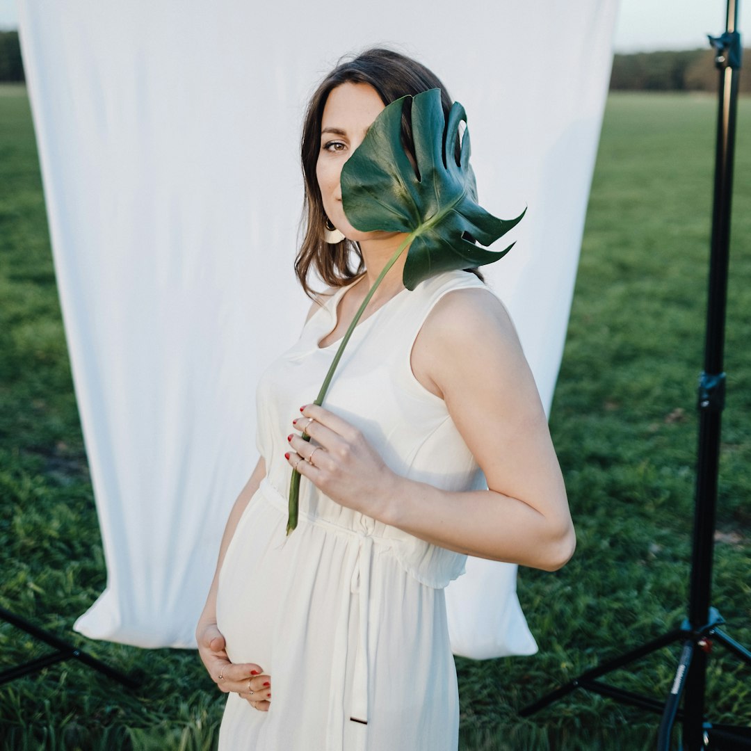 woman in white sleeveless dress standing on green grass field during daytime