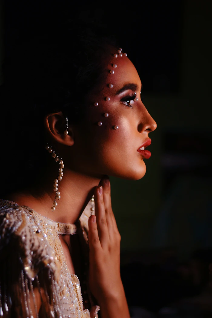 Mujer de perfil con maquillaje de noche y pequeños brillos en el pómulo