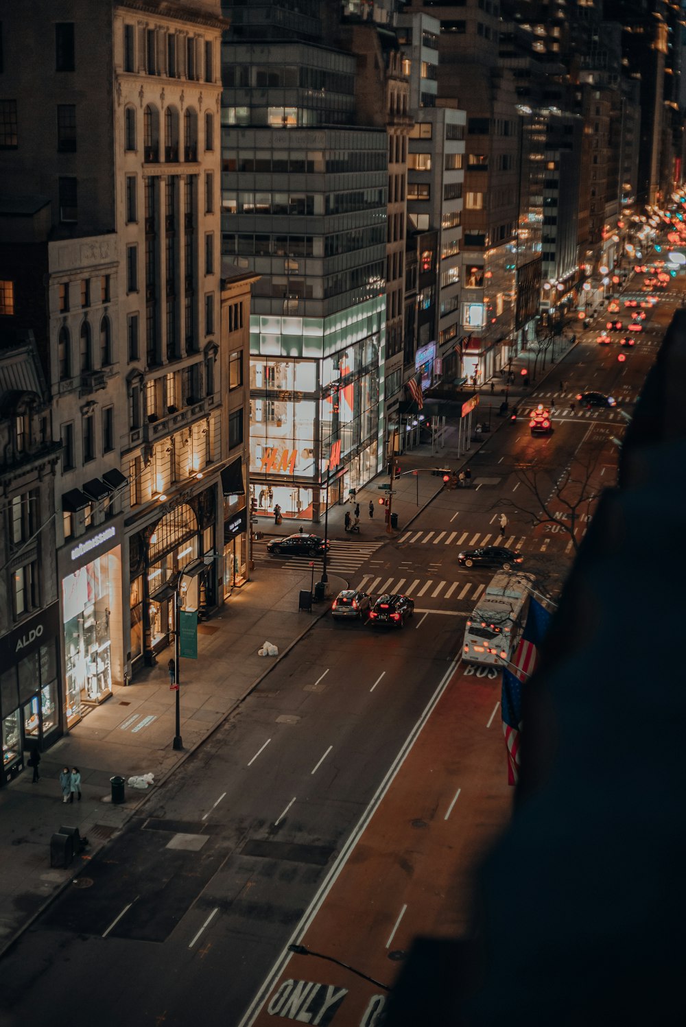 cars on road between high rise buildings during night time