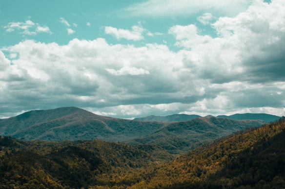 green and brown mountains under white clouds and blue sky during daytime
