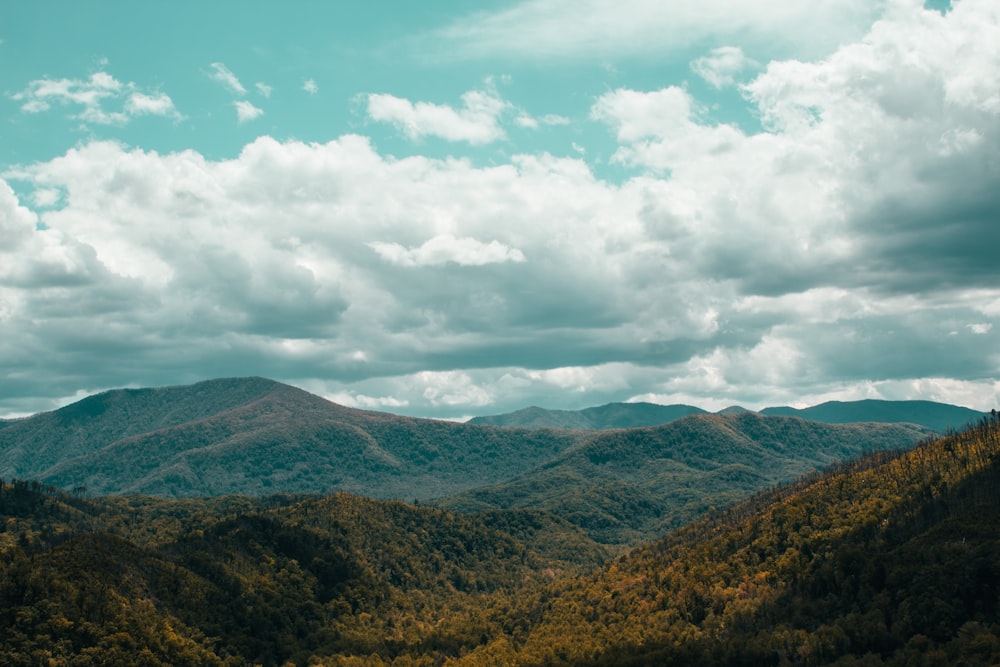 green and brown mountains under white clouds and blue sky during daytime