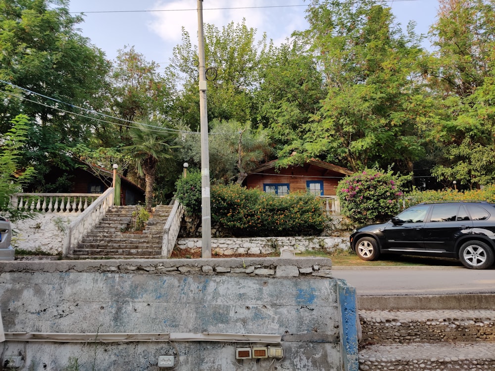 Sedán negro estacionado cerca de un edificio de concreto marrón durante el día