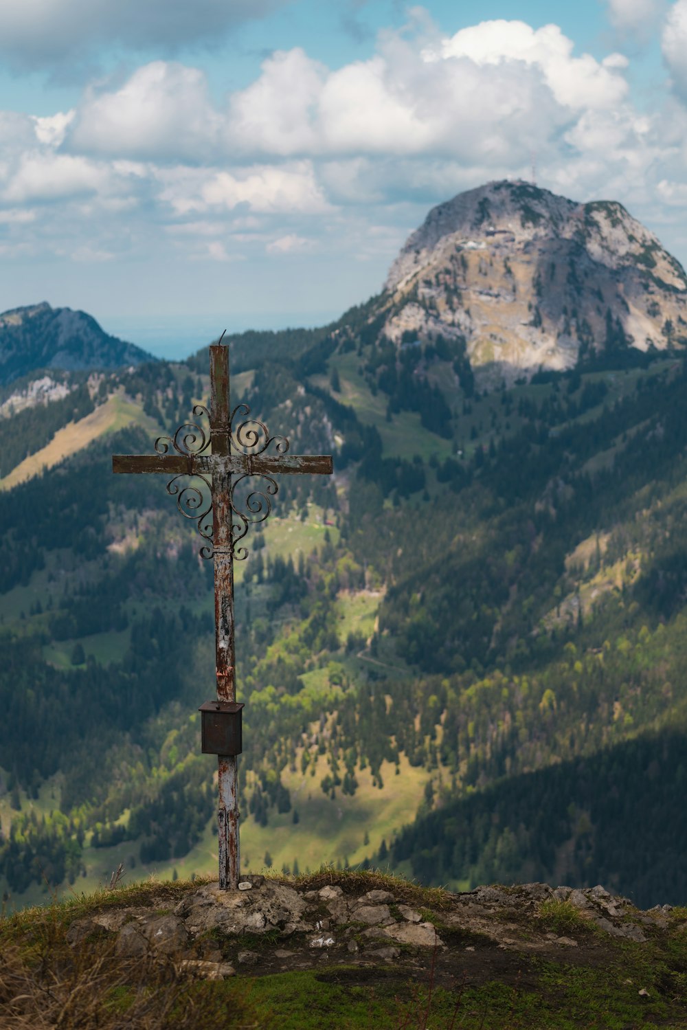 cruz marrom no topo da montanha durante o dia