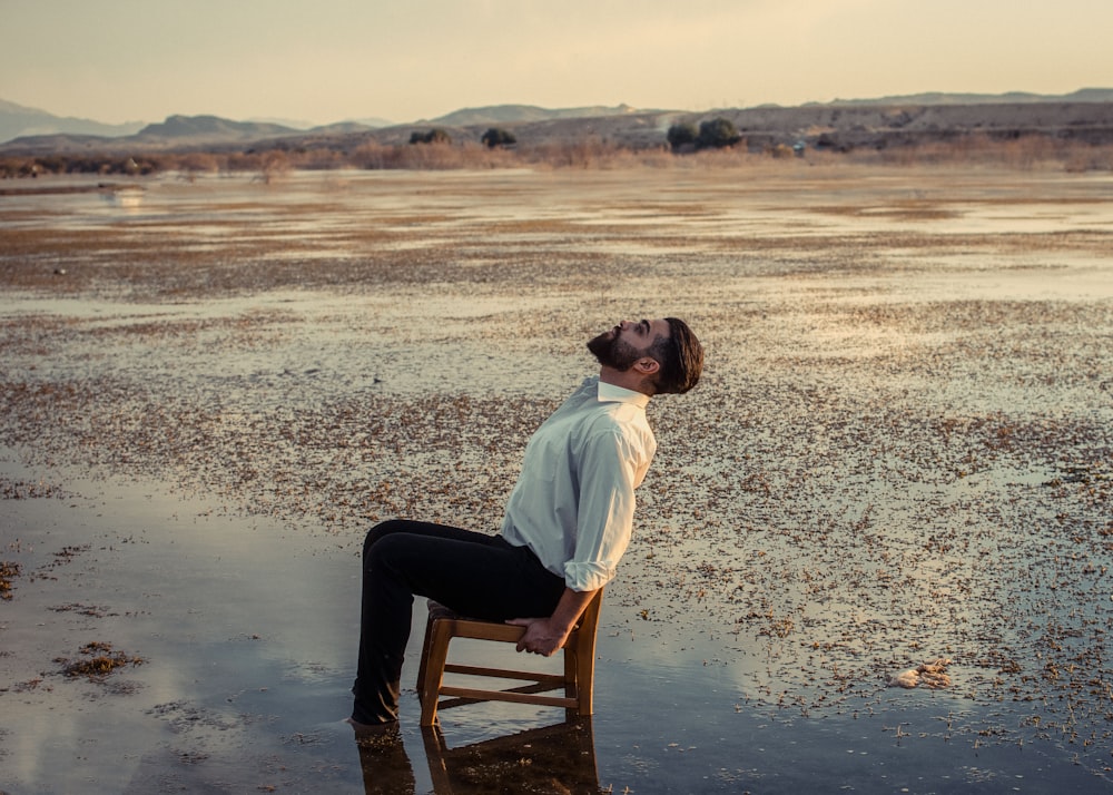 man in white dress shirt sitting on brown wooden chair