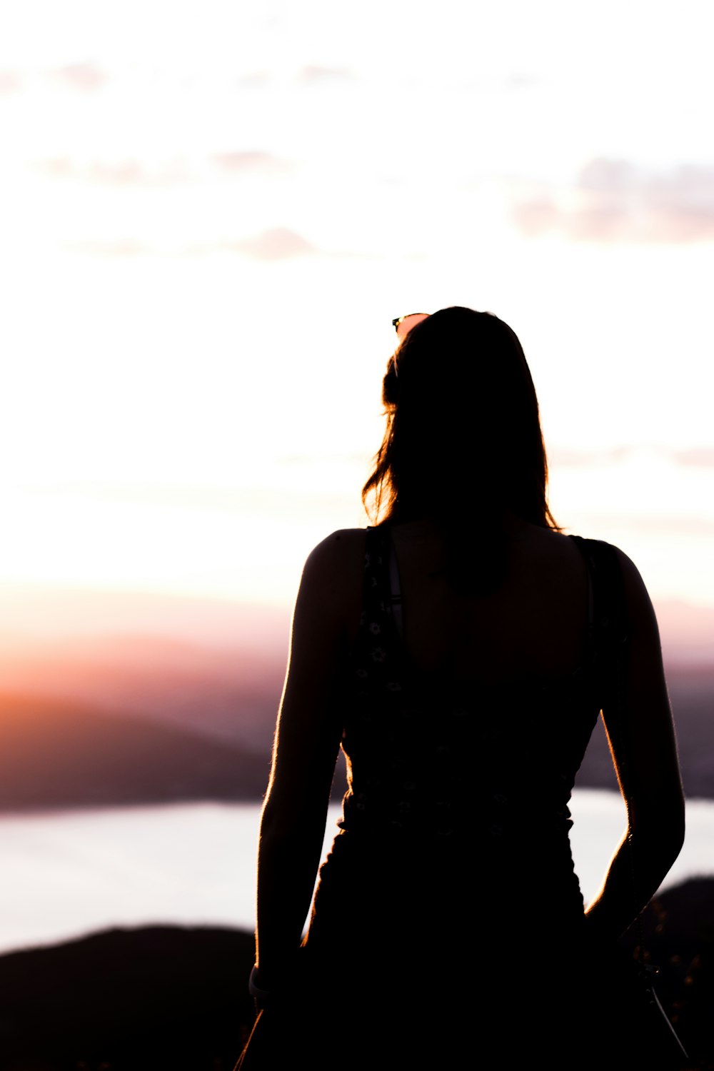 femme en débardeur noir debout sur la plage pendant le coucher du soleil