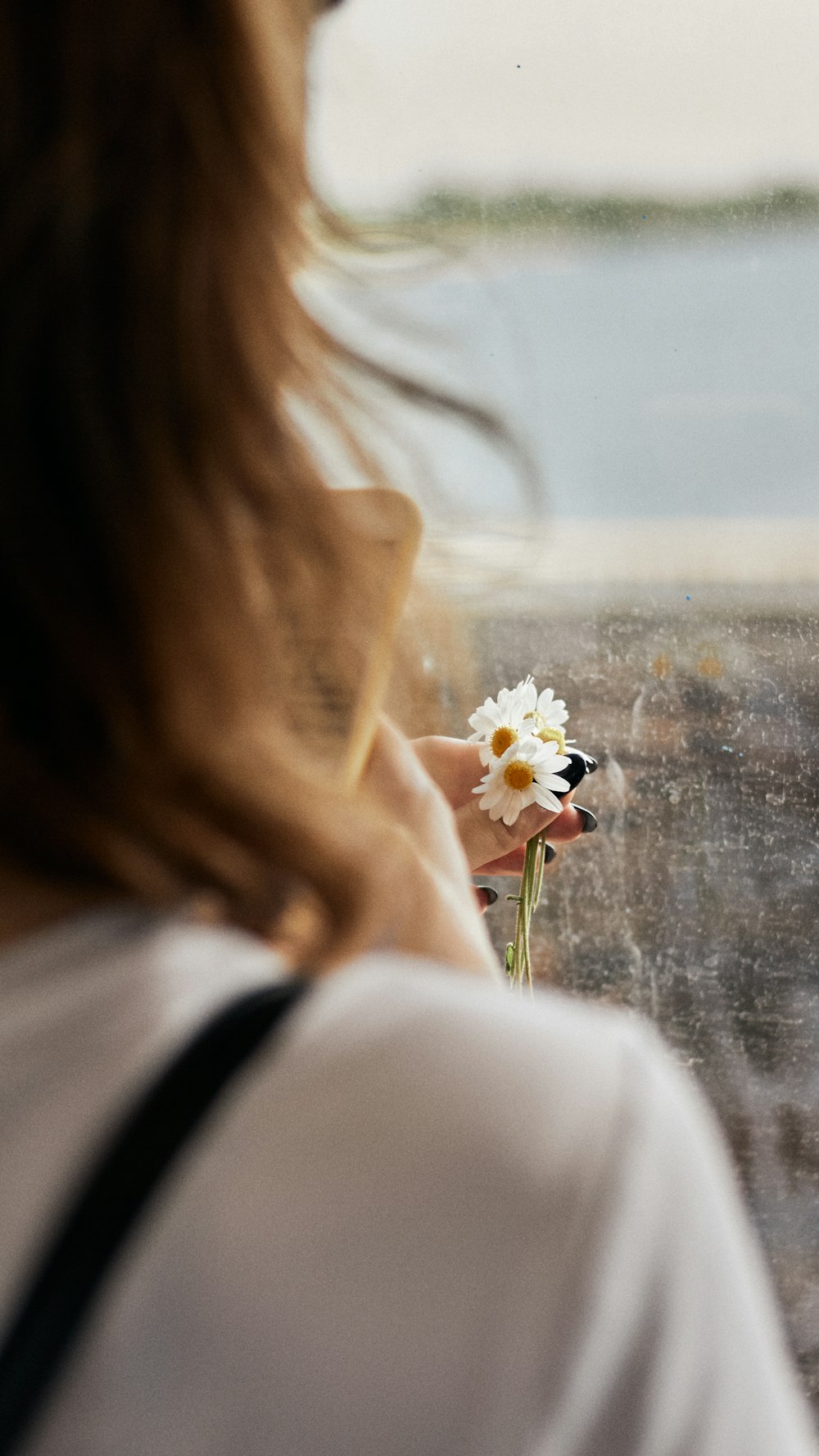 woman in white long sleeve shirt holding white flower