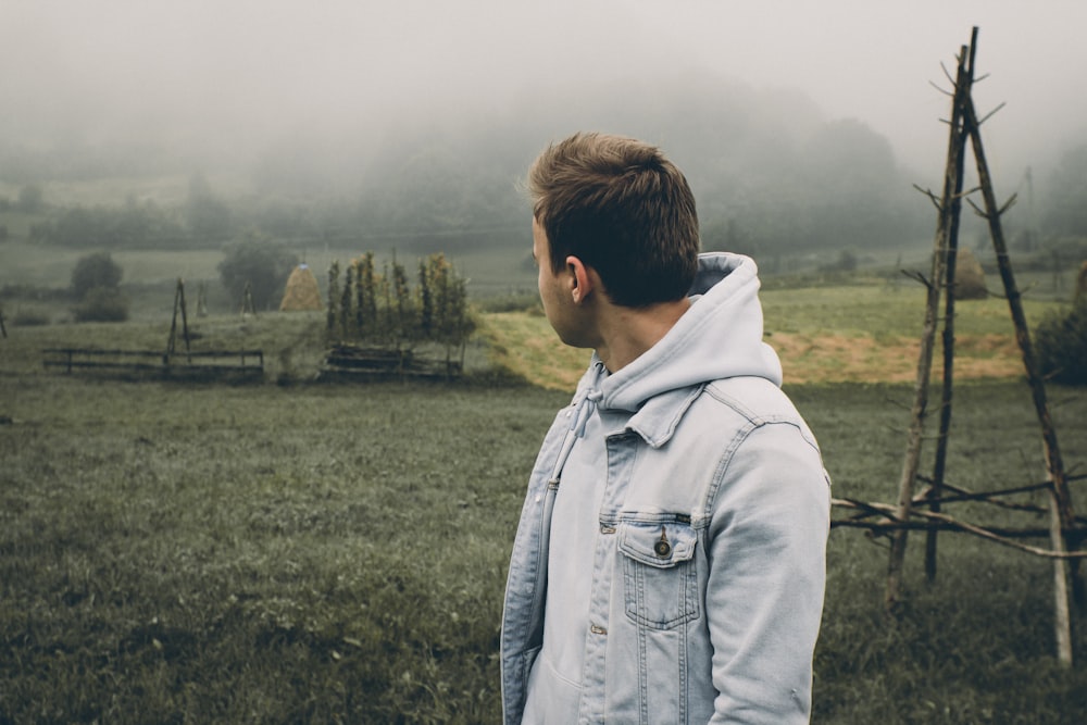 man in gray jacket standing on green grass field during daytime