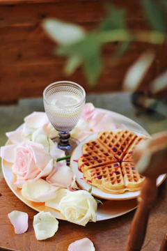Close-up of heart-shaped waffles and mini hotcakes topped with fresh fruit and chocolate on a festive party table.