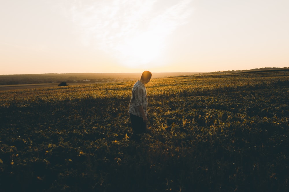 person in white long sleeve shirt standing on green grass field during daytime