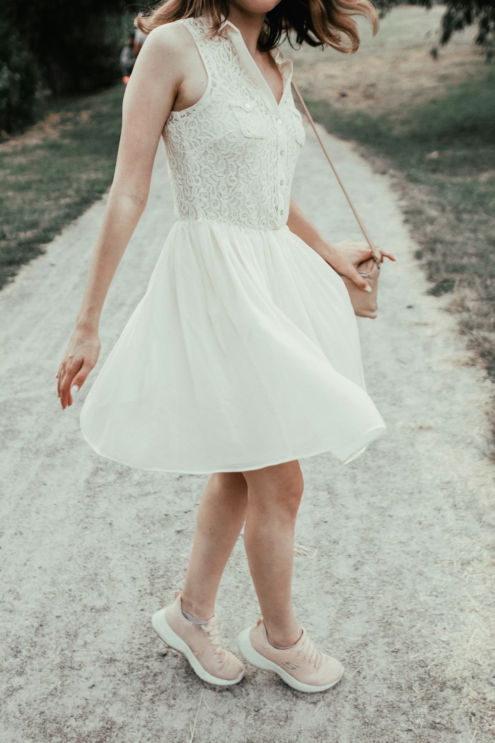 woman in white sleeveless dress holding brown wooden stick