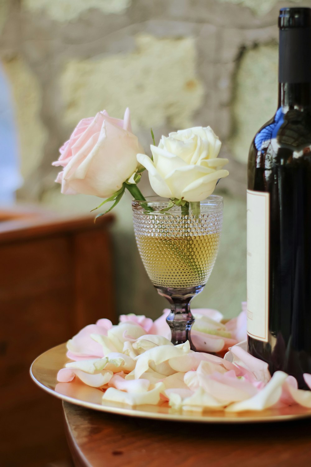 透明なワイングラスに入った白とピンクのバラ