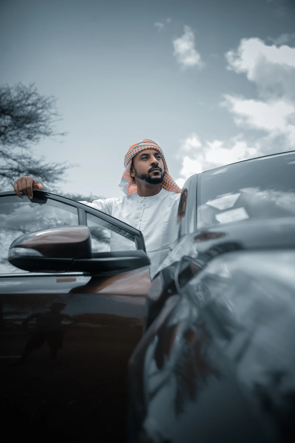 Man in a white thobe standing beside his car