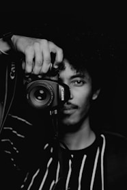 man in black and white crew neck shirt holding black nikon dslr camera