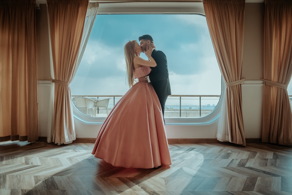 woman in red dress standing beside window