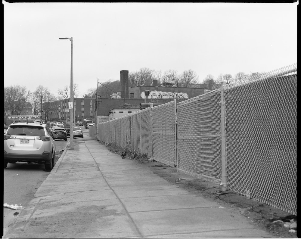 grayscale photo of a road with metal fence