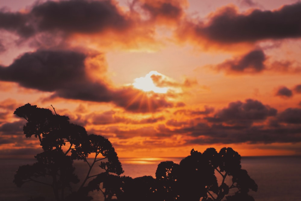 the sun is setting over the ocean with clouds