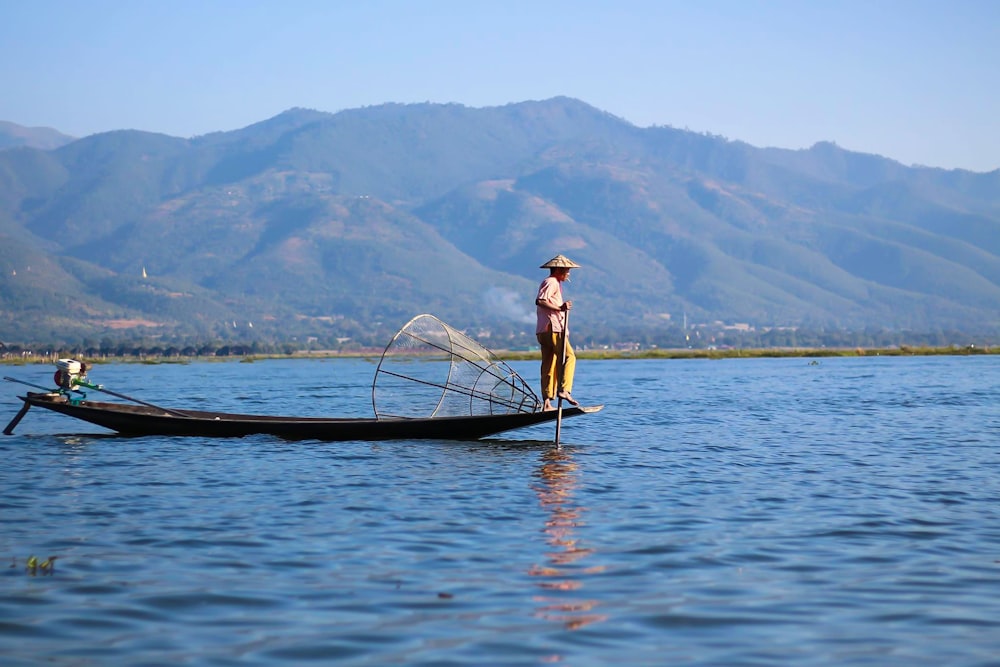 woman in white shirt and brown hat standing on boat on body of water during daytime