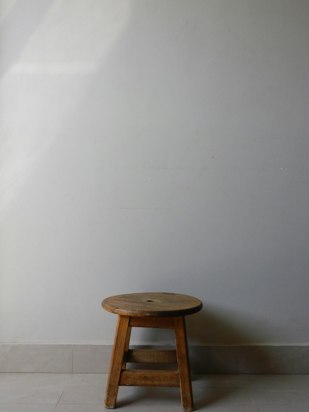 un pequeño taburete de madera contra una pared blanca