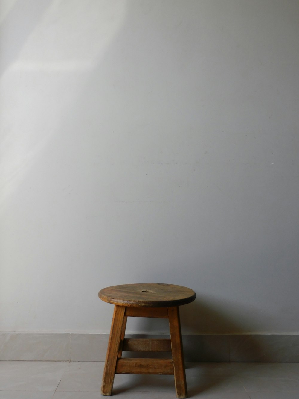 un petit tabouret en bois contre un mur blanc