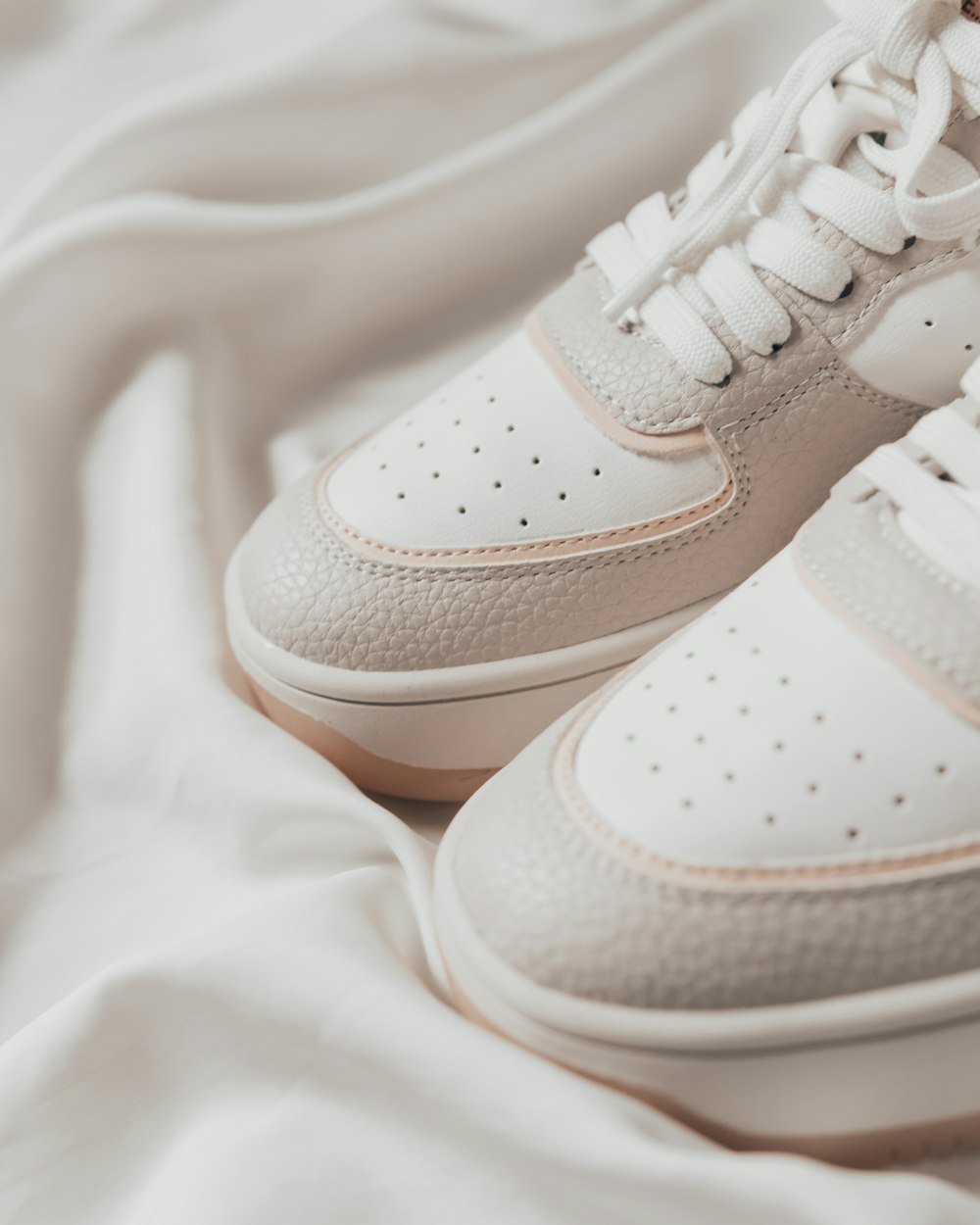 a pair of white sneakers sitting on top of a bed