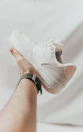 a person holding onto a white tennis shoe