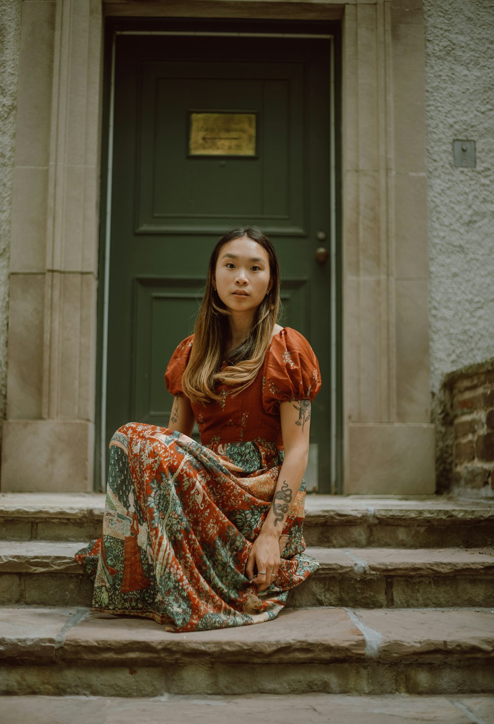 a woman sitting on steps in front of a green door