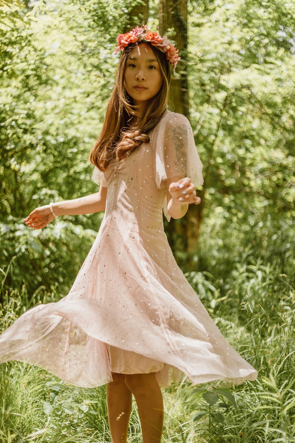 a little girl in a dress standing in the woods