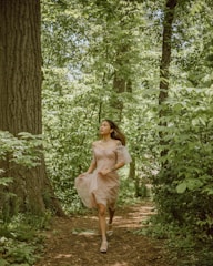 Model wearing a flowing dress walking through a sunlit urban park.