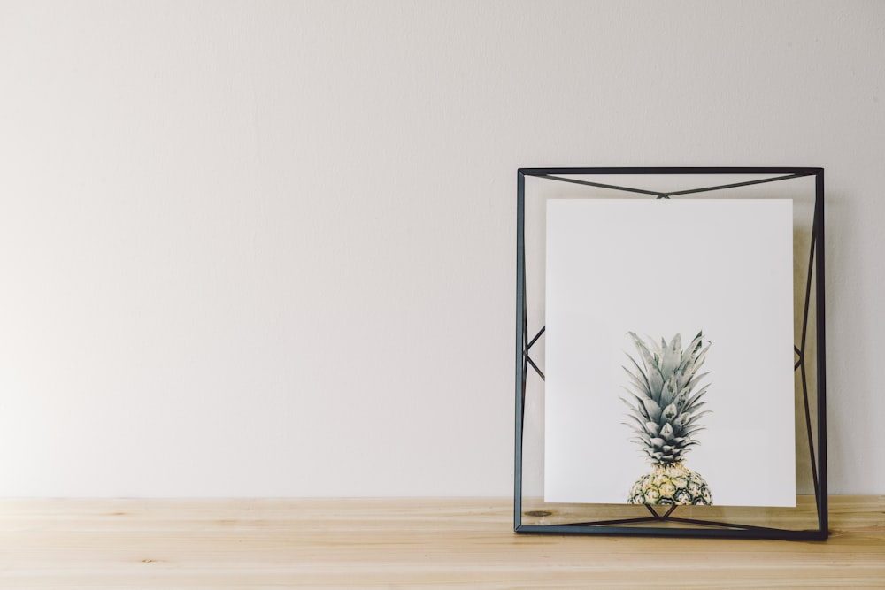 a picture of a pineapple in a frame on a table