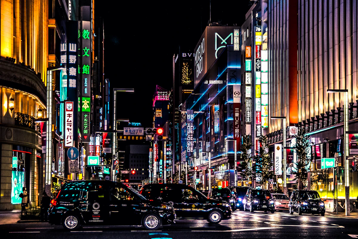 Ginza at night, neon kanji billboards, taxis at the curb