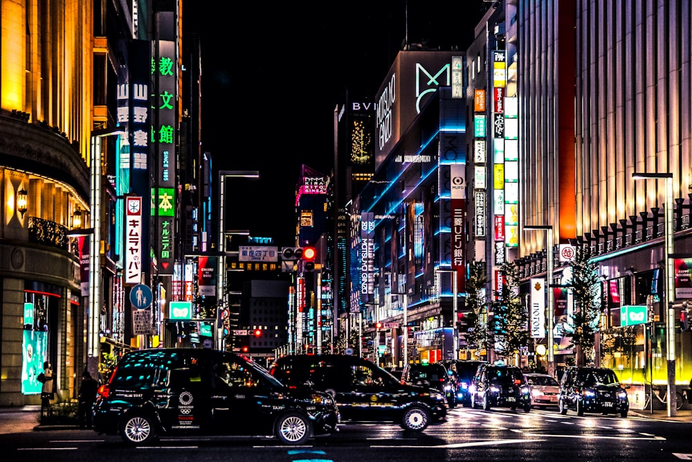 cars on road between high rise buildings during night time