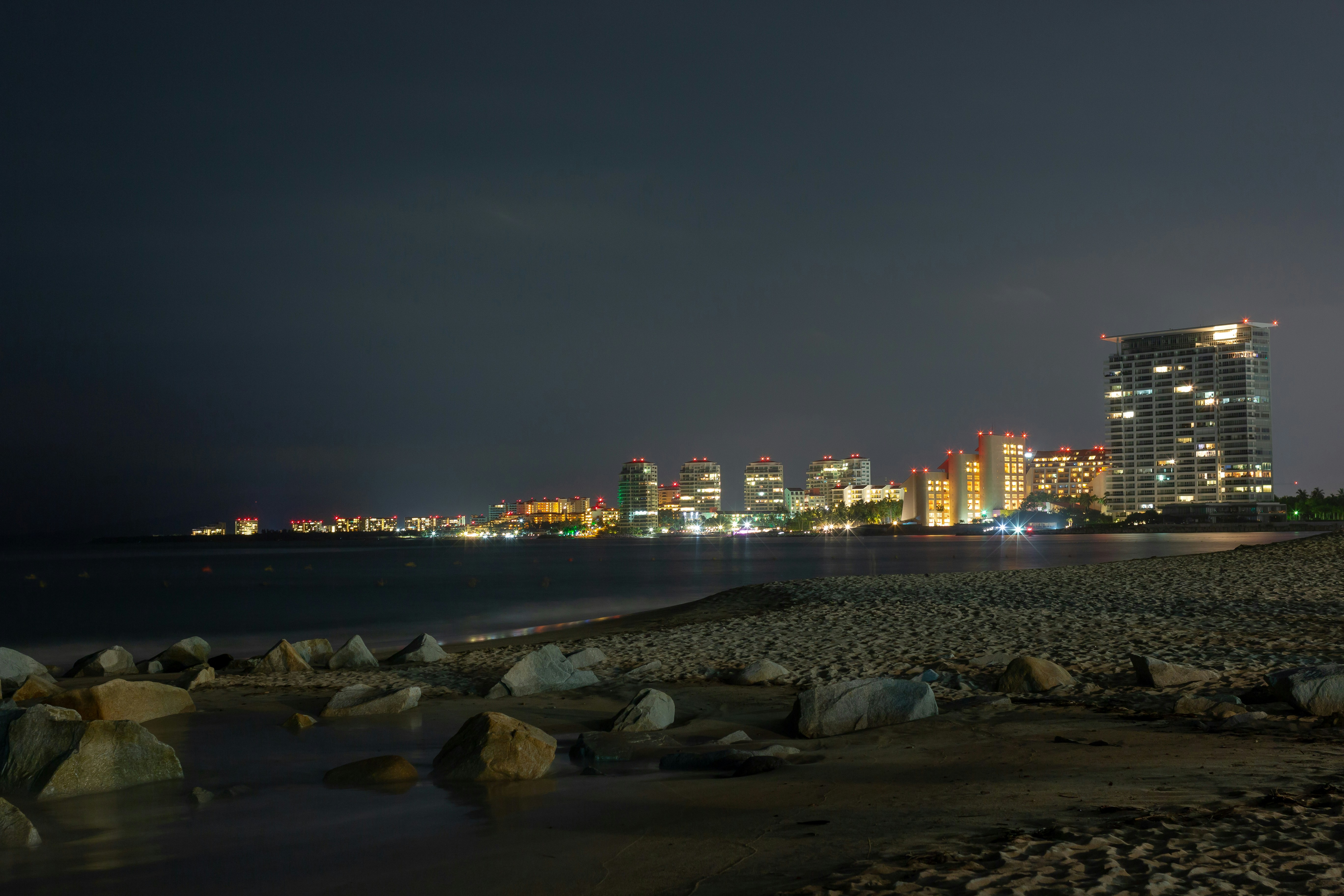 city skyline across body of water during night time