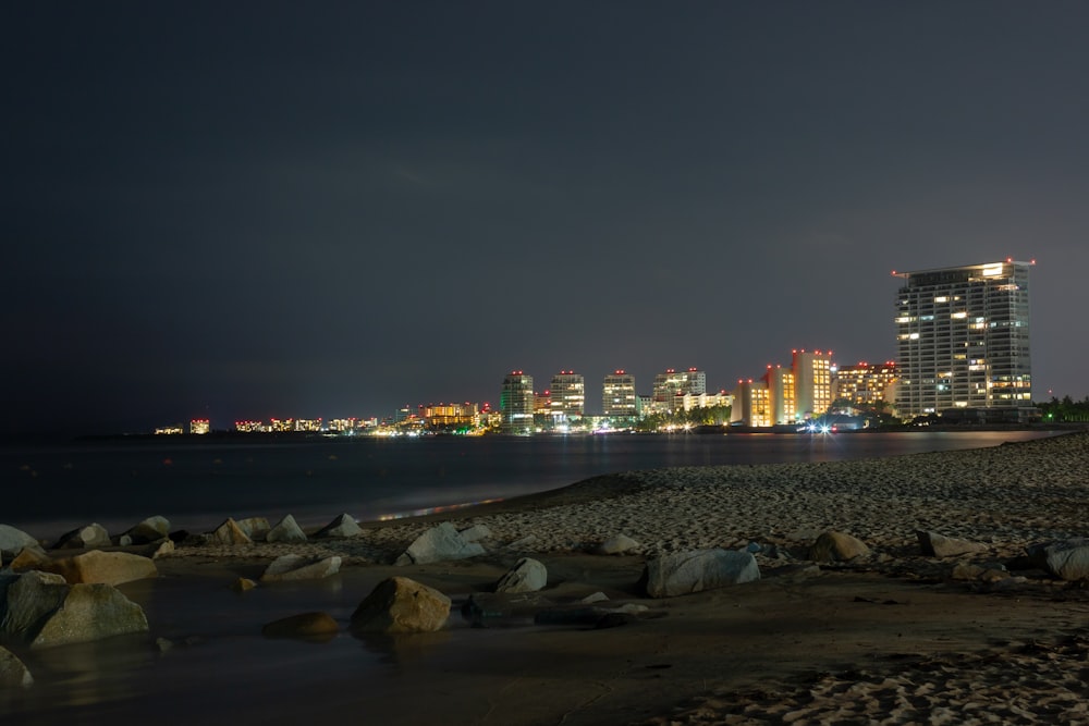 city skyline across body of water during night time