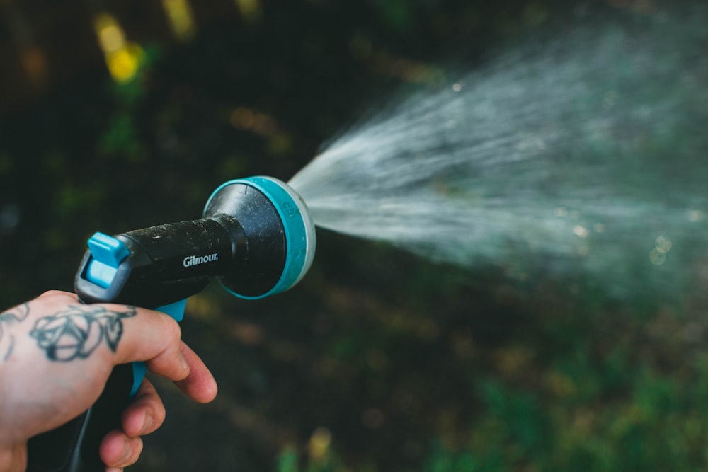 person holding blue and black water pump