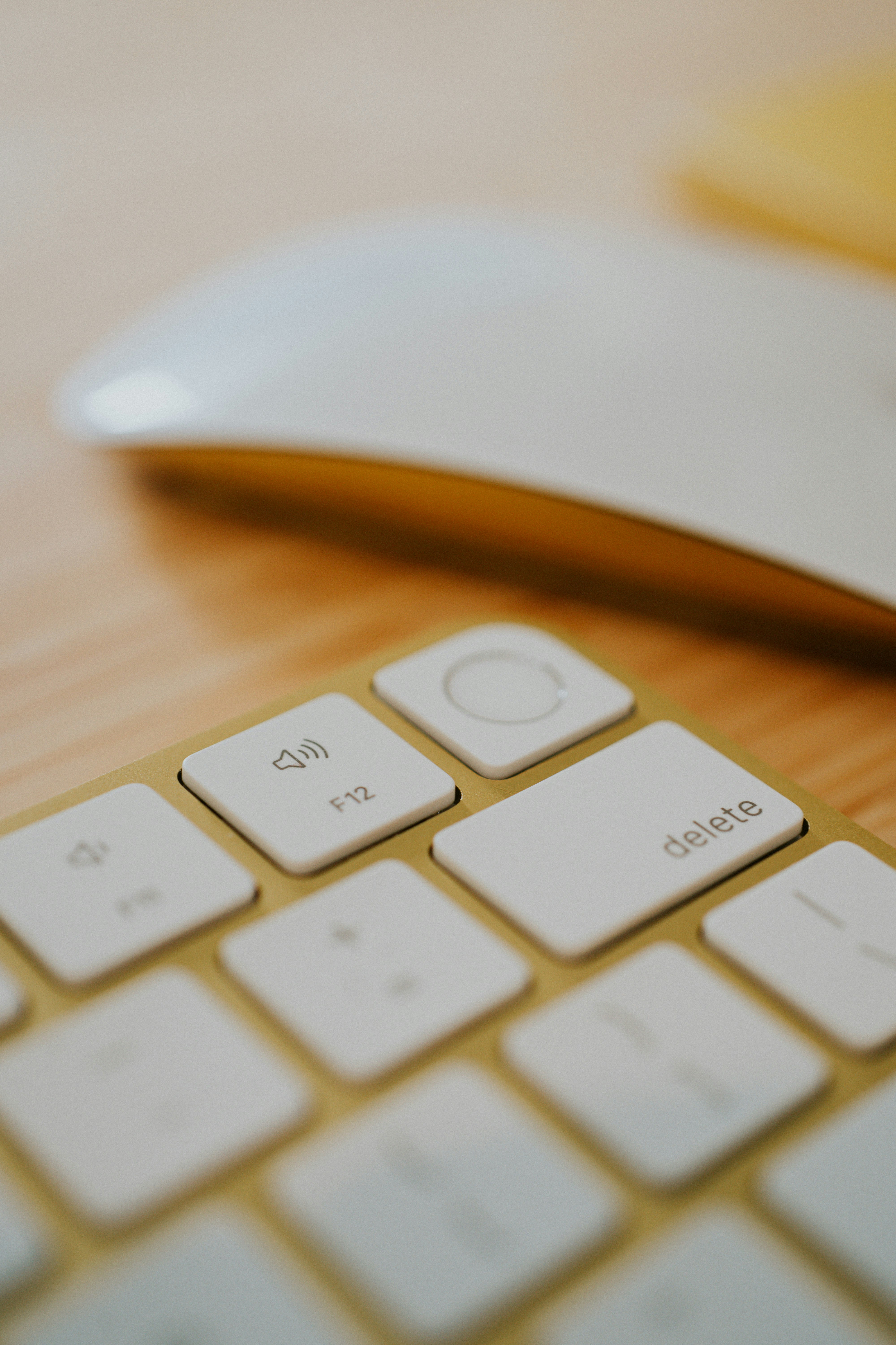 Yellow Apple keyboard with Touch ID fingerprint scanner with yellow Magic Mouse on a desk in a home office.