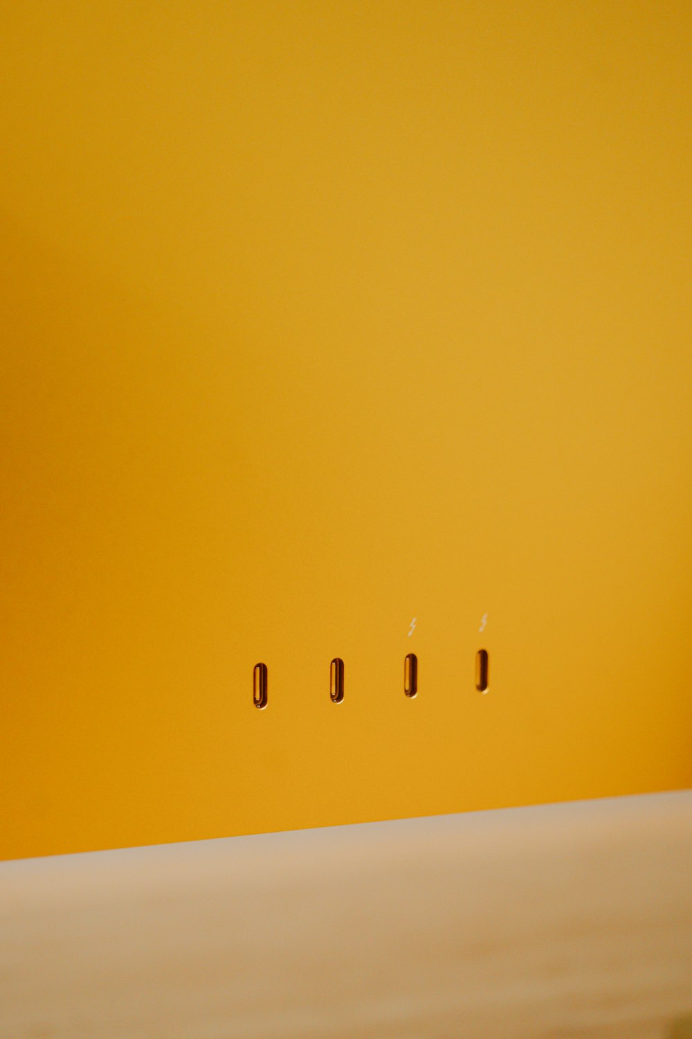 a yellow wall with four small screws on it