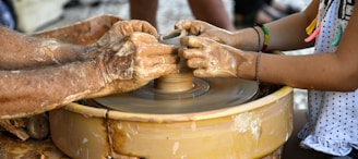 a woman is making a pot on a wheel