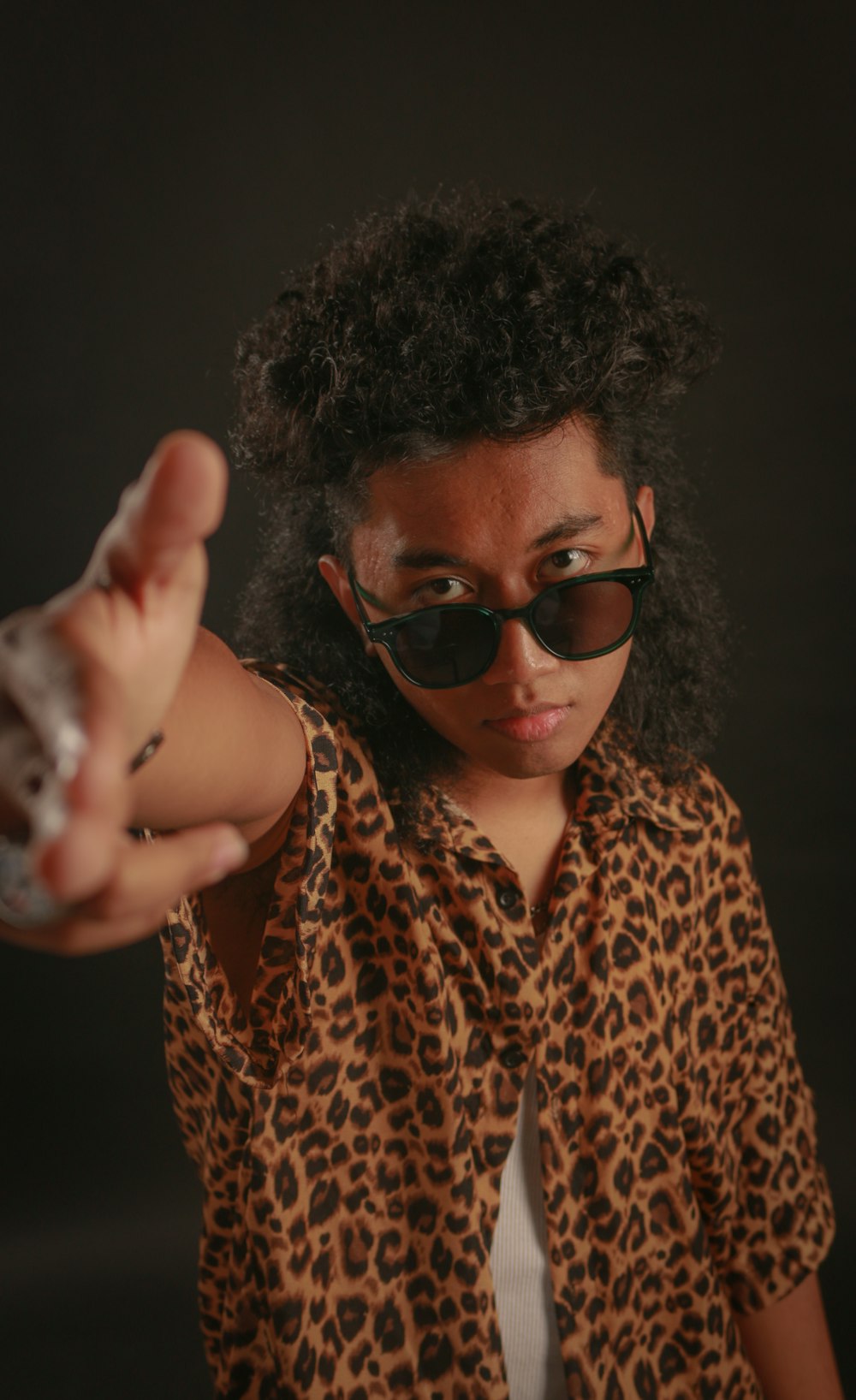 a woman in a leopard print shirt pointing at the camera