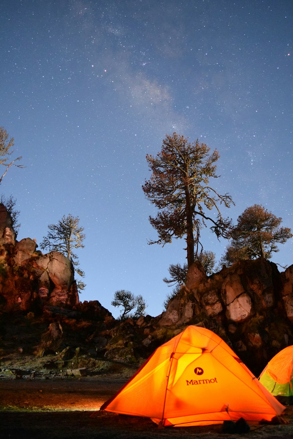 yellow tent on brown rock formation under blue sky during night time