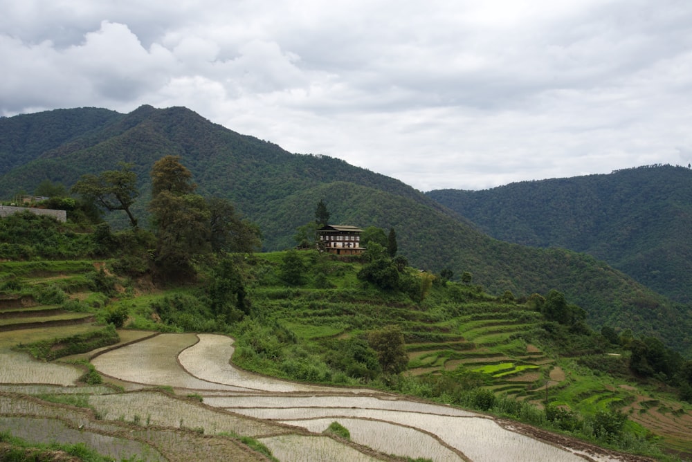 brown house on green grass field near mountain under white clouds during daytime